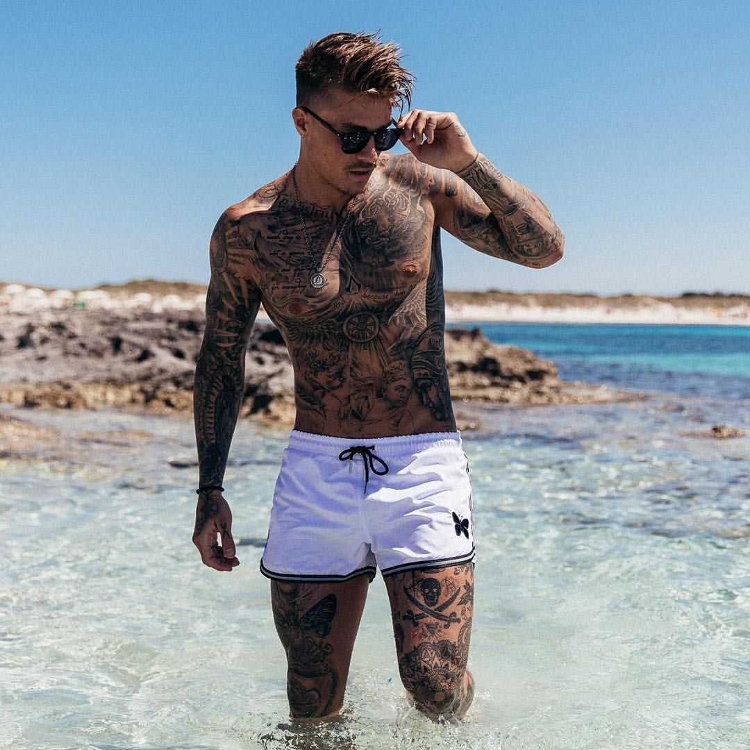Мужчина пляже в татуировках